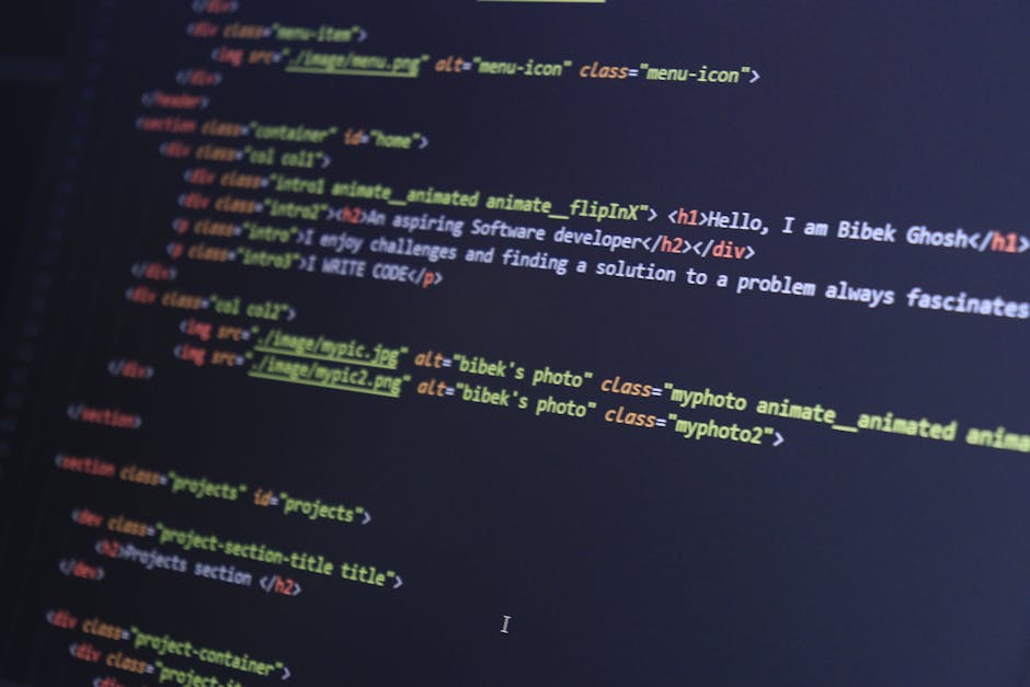 A photograph of a computer screen displaying lines of colourful HTML and CSS code, with syntax highlighting for tags, attributes, and values, in a dark theme background. The code sequences include ele